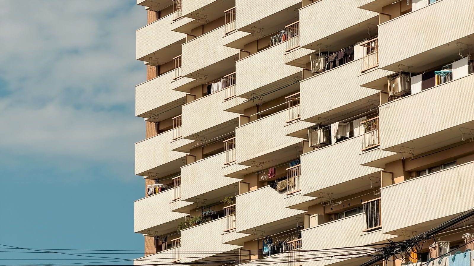 青空を背景にした集合住宅の外壁